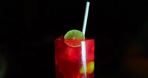 Refreshing Red Cocktail with Lime Slice in Dark Lounge Bar Stock Footage 344916731