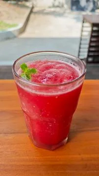 Refreshing Red Watermelon Juice with Mint Garnish on a Wooden Table in a Su.. Stock Photos