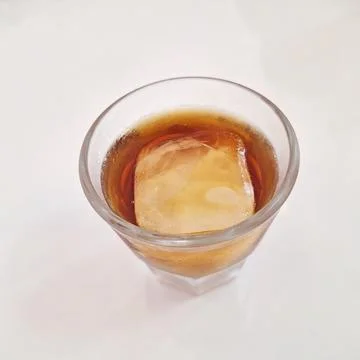 Refreshing Single Ice Cube Whiskey or Iced Tea Drink in a Short Glass. Stock Photos