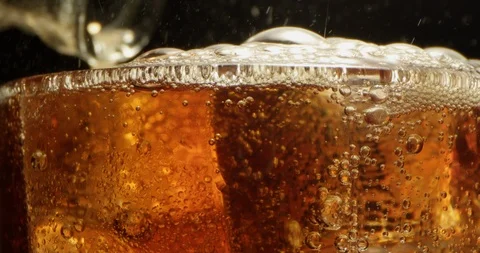 Refreshing Soda Drink Pouring with Bubbles Floating on Ice Cubes in a Glass Video stock 123977232