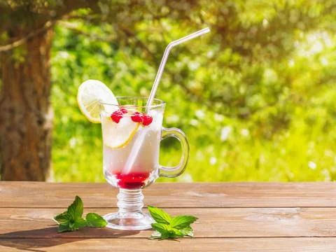 Refreshing summer cocktail with lemon, raspberry and mint a wooden table Stock Photos