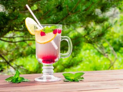 Refreshing summer cocktail with lemon, raspberry and mint a wooden table Stock Photos