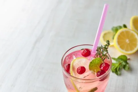 Refreshing summer drink with berry and lemon on a light wooden table. The con Stock Photos