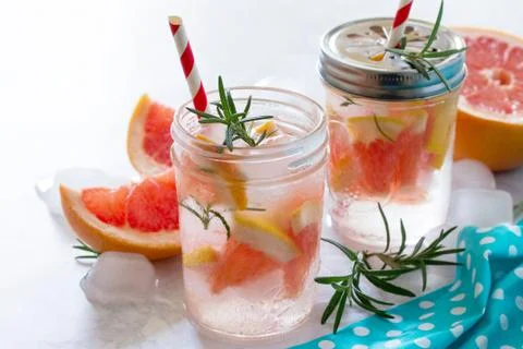 Refreshing summer drink with grapefruit and rosemary on a stone background. Stock Photos