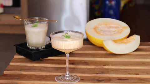 Refreshing summer drink with melon and mint in elegant glasses on wooden table Video stock 313794028