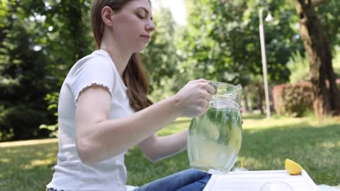 Refreshing summer drink preparation in a serene garden setting Stock Footage 297360960