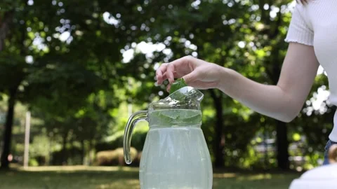 Refreshing summer drink preparation in a sunny park setting Stock Footage 297370253