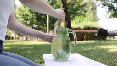 Refreshing summer drink preparation in a sunny outdoor garden setting Stock Footage 297370284