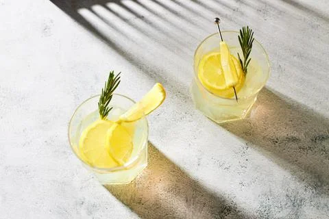 Refreshing summer drinks with fresh lemon garnished with a sprig of rosemary on Foto stock
