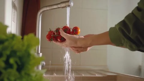 Refreshing tomatoes under cool water while preparing for a healthy meal in a Stock-Footage 294914193