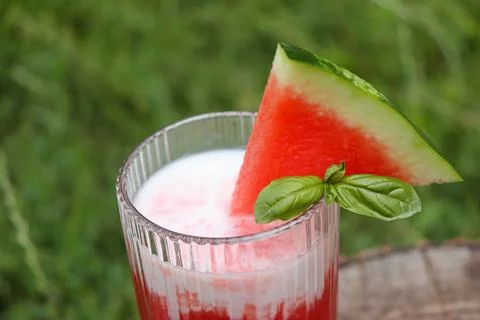 Refreshing watermelon drink topped with basil in a glass on a sunny day Stock Photos
