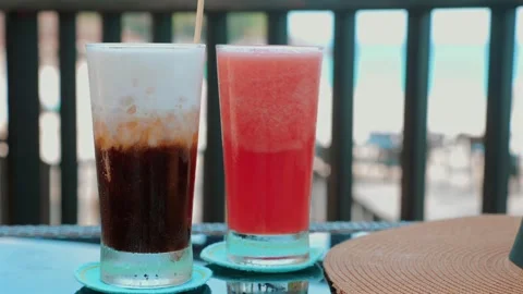 Refreshing watermelon juice and iced coffee on wooden table at beach resort Stock-Footage 247370965