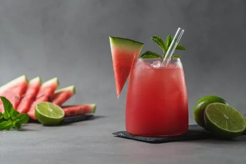 Refreshing watermelon mocktail with lime, mint and ice stands on gray table 库存照片
