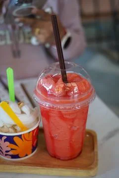 Refreshing watermelon smoothie in plastic cup served with coconut ice cream on w Stock Photos