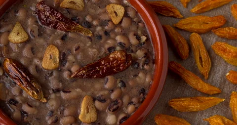 Refried beans with fried garlic and chili. Dried chilies on the table. Stock Footage 297294740