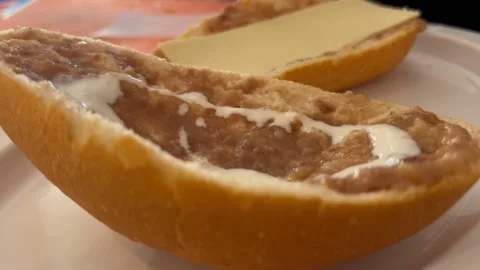 Refried beans spread on a piece of bread with a slice of cheese on the Stock Footage 290374857