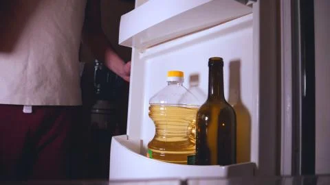 Refrigerator view from the inside, a man takes milk. Stock Photos
