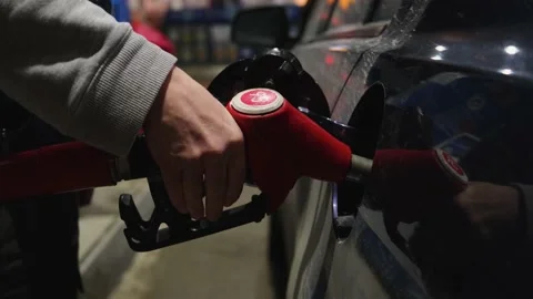 A refueling gun in a man's hand is inserted into the gas tank of a car. Stock Footage 150700171
