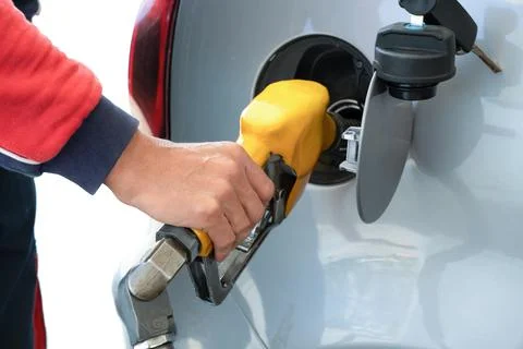 Refueling gun in the man's hand, while refueling car with gasoline fuel, at gas Stock Photos