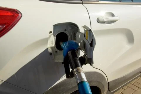 A refueling nozzle is inserted into the tank of the car. At the gas station the Stock Photos
