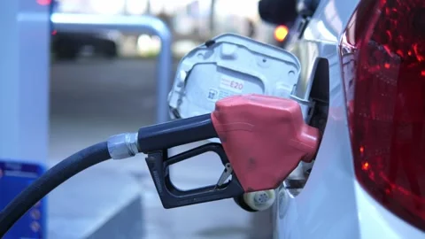 Refueling a silver car with a fuel nozzle at a gas station for energy, oil price Video stock 332299888