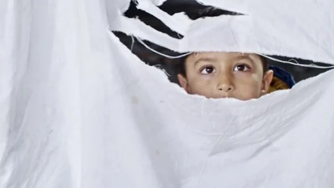 Refugee Boy Looking through Hole in Cloth Stock Footage 78738148