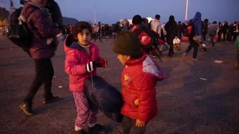 Refugee children looking at camera while leaving on Mytilene port at night Stock Footage 145916099