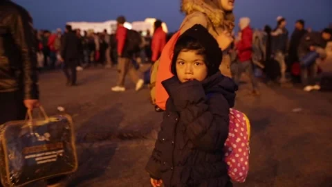 Refugee kid looking at camera while leaving on Mytilene port at night 스톡 동영상 145916087