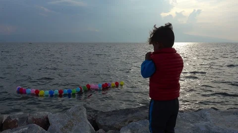 Refugee Syrian Little Boy Looking at Balloons at Sea Stock Footage 120322682
