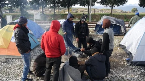 Refugees and migrants wait on the Greece-Macedonia border near Idomeni Vídeo Stock 99181778