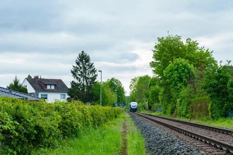 A regional train is approaching on rails on a cloudy day. Stock Photos