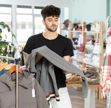 Regular customer guy chooses color and style of sweater Stock Photos