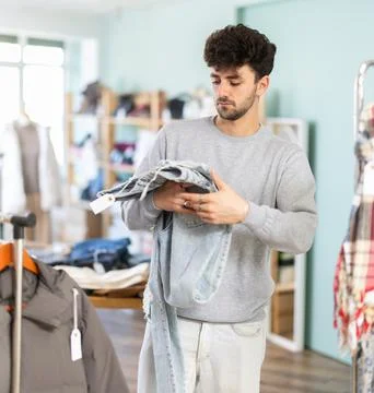 Regular customer guy chooses color and style of jeans trousers Stock Photos