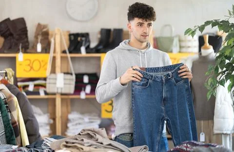 Regular customer guy chooses color and style of jeans trousers Stock Photos