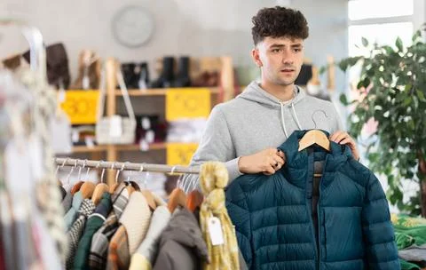 Regular customer guy chooses color and style of down jacket Stock Photos