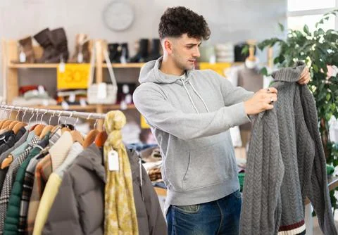 Regular customer guy chooses color and style of sweater Stock Photos
