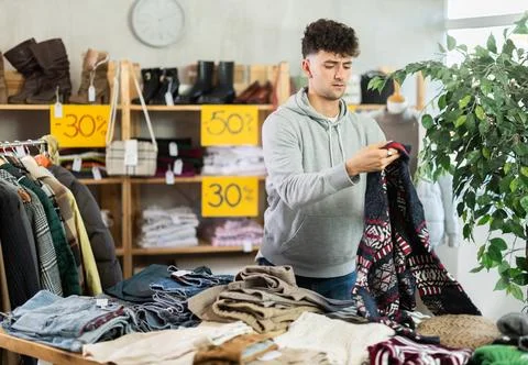 Regular customer guy chooses color and style of sweater Stock Photos