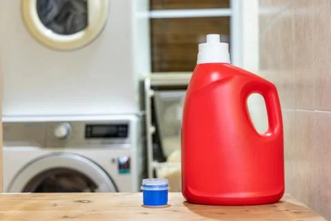 Regular liquid laundry detergent against washing machine background Stock Photos