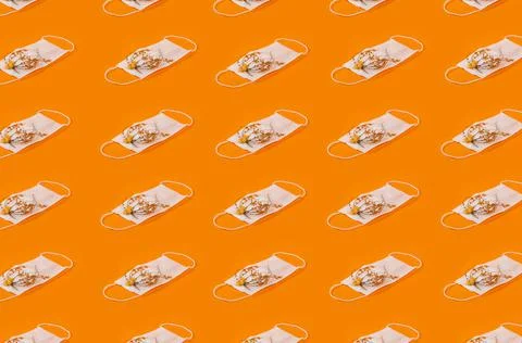 Regular Pattern Of Medical Face Masks With Flowers And Orange Background. Stock Photos