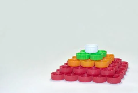 Regular quadrangular pyramid of whites, reds, greens, oranges striped caps of Stock Photos