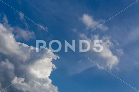 Regular spring clouds on blue sky at daylight. Close shot wit telephoto lens and Stock Photos