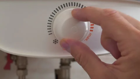 Regulator for heating water in boiler. Man turns temperature control on heater Stock Footage 320733222