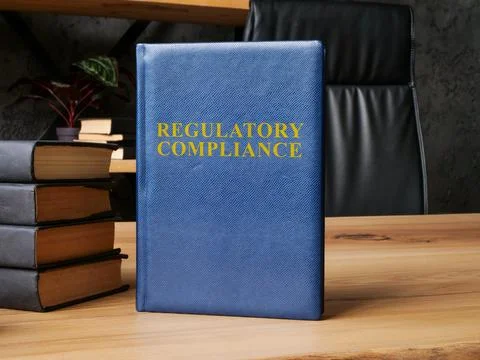 Regulatory compliance laws next to stack of books. Stock Photos