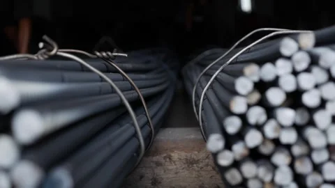 Reinforcement bars with green ends lie bundled in rows near pavement, waiting Stock Footage 313668502