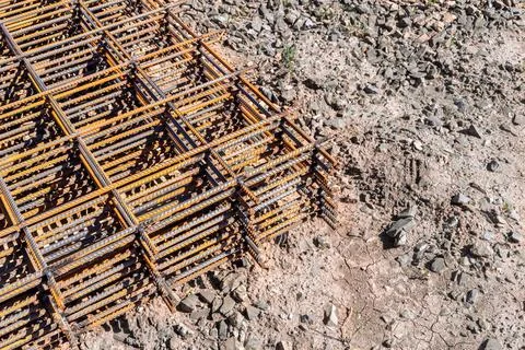 Reinforcing frame mesh covered with rust lies on the ground, waiting to be ra Stock Photos