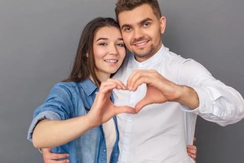 Relationship Concept. Young couple studio standing isolated on grey hugging Stock Photos