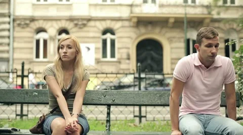 Relationship difficulties, couple sitting in park, steadicam shot HD Stock Footage 11884181
