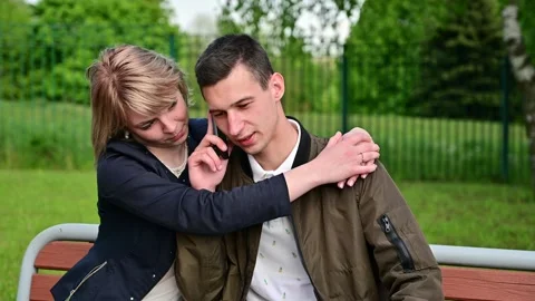 Relationship problems. Young couple are hugging while sitting on a bench  Video stock 132319627