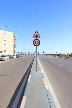 A Relatively Empty Two Ways Street With Bumpy Road and Speed Limit of 30 Sign Stock Photos