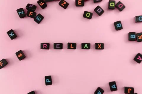 Relax button concept. Black beads on pink background making word Foto stock